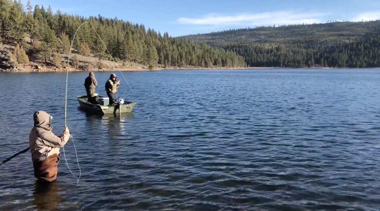 Three anglers fly fishing together, one wading and two fishing from a boat, on Round Valley Reservoir